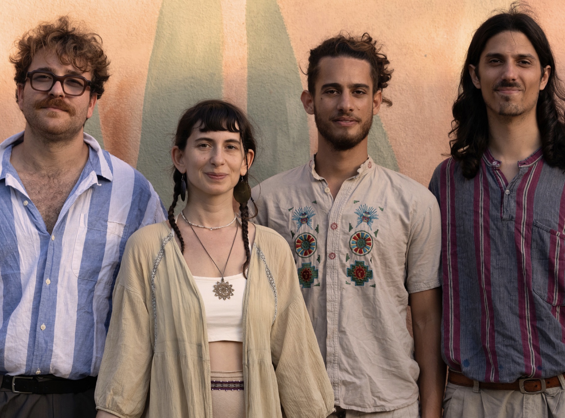 The four members of Cloud Of I standing against a painted peach wall